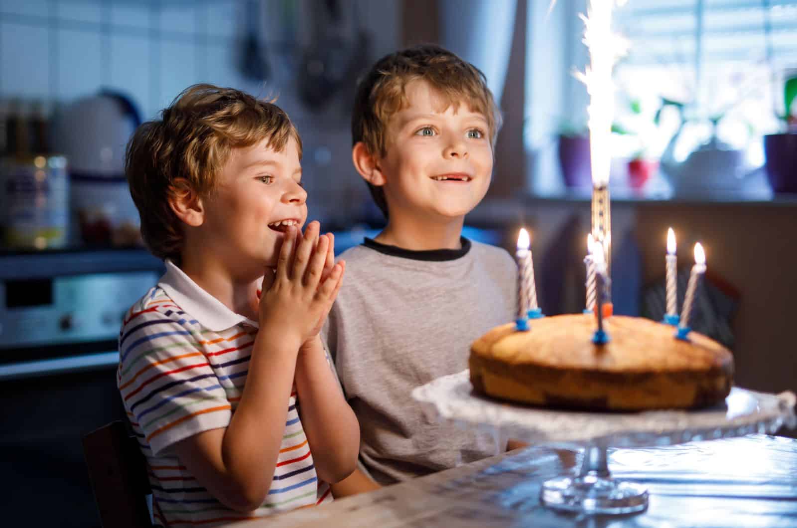 two boys blowing out candles on cake