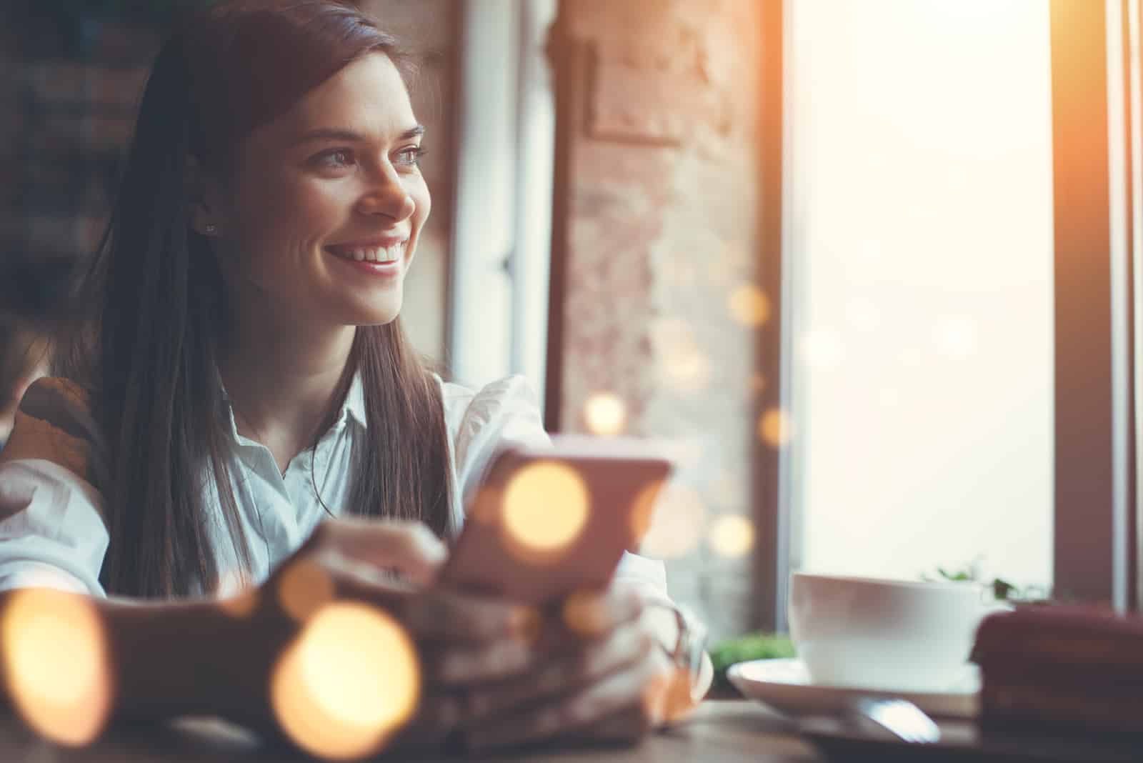 Smiling woman in cafe using mobile phone