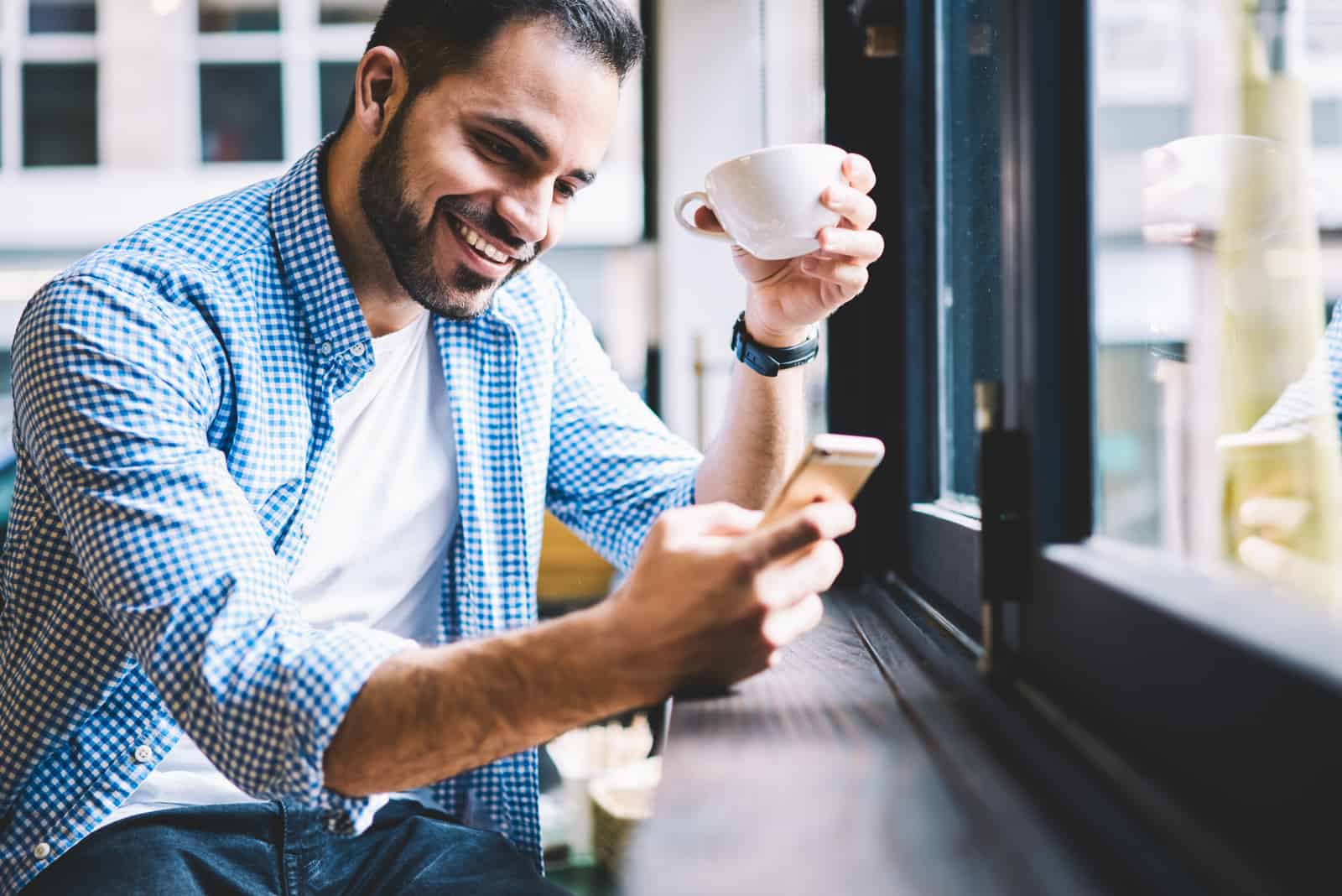 hombre sentado en un café enviando mensajes de texto