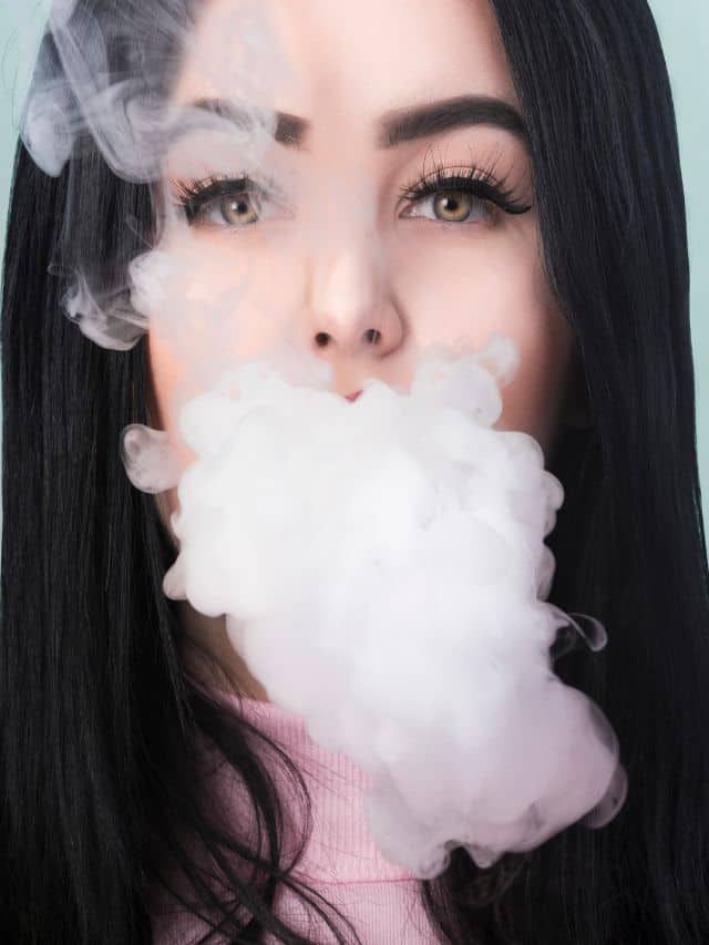 a girl with a dark hair and green eyes smoking