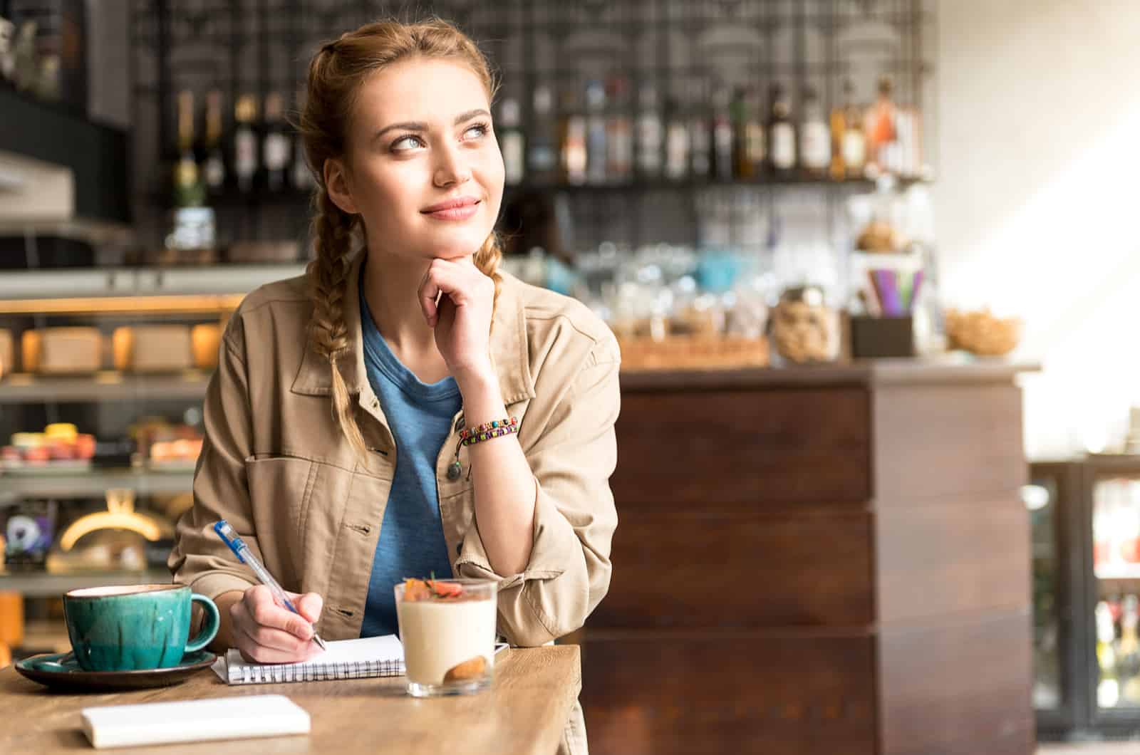 mujer escribiendo en un cuaderno mientras está sentado en un café