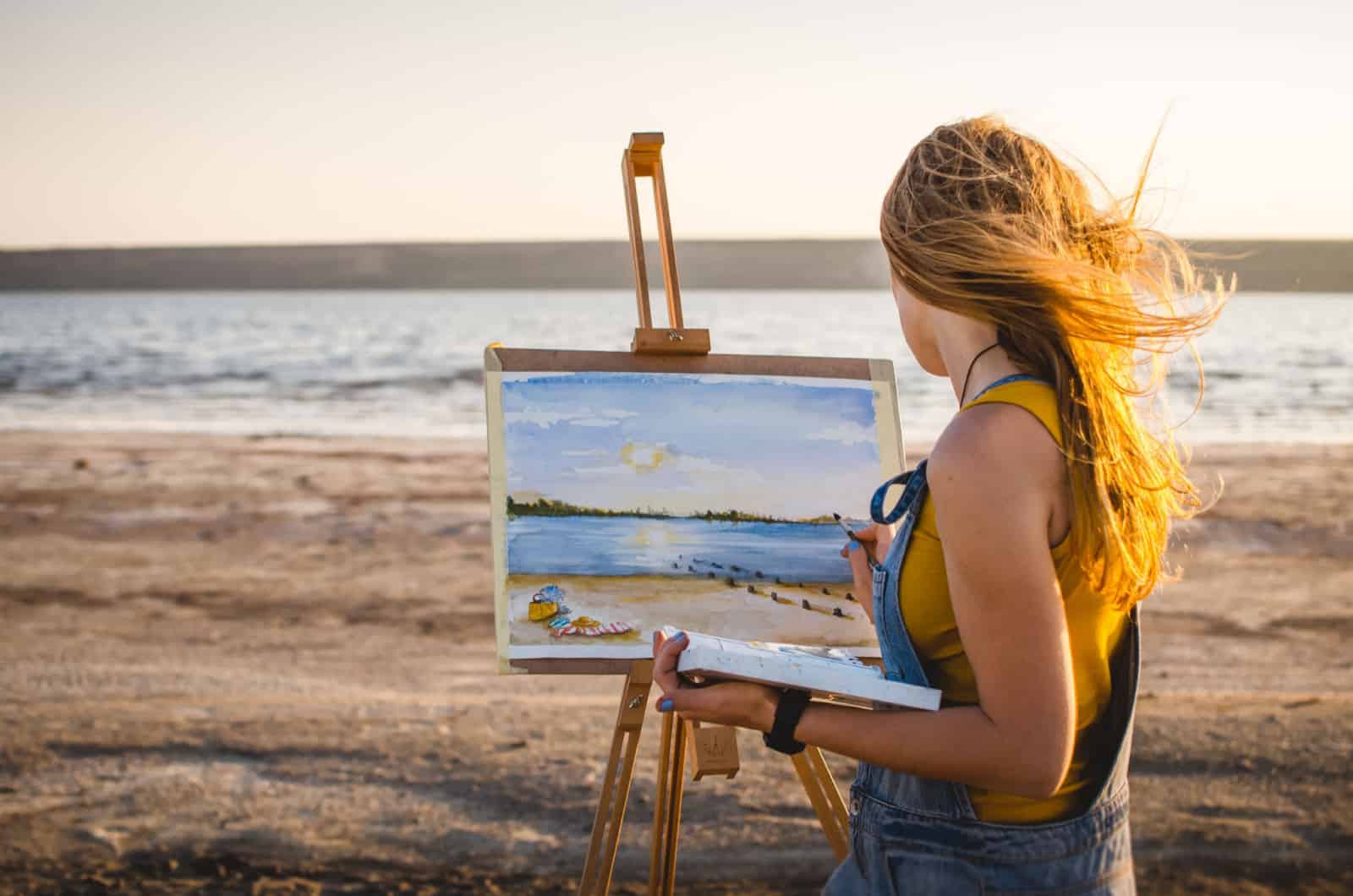 mujer pintando a la orilla del mar