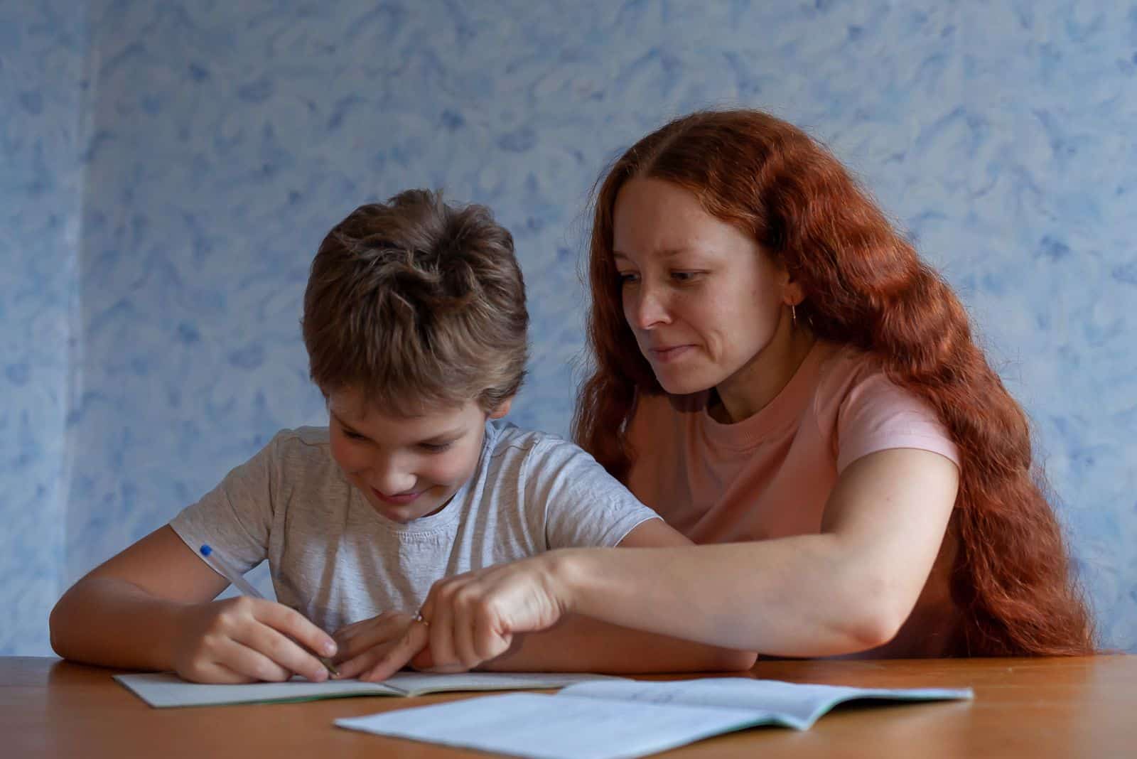 el niño está sentado leyendo junto a su madre