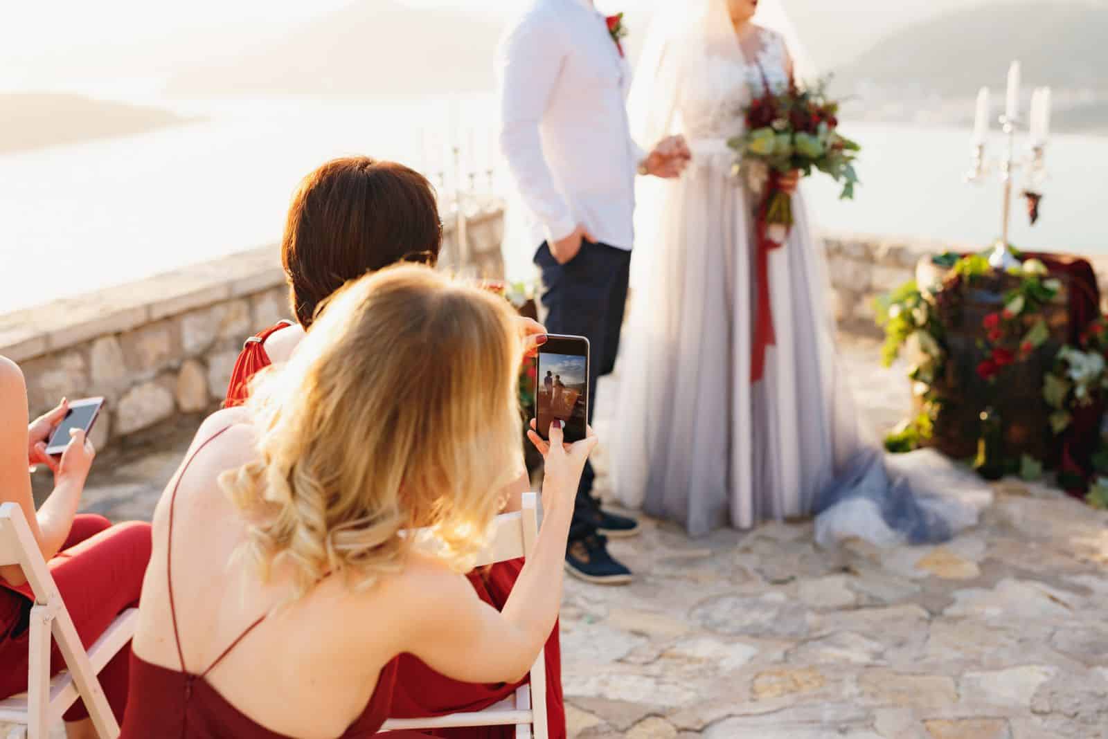 blonde haired woman filming a wedding