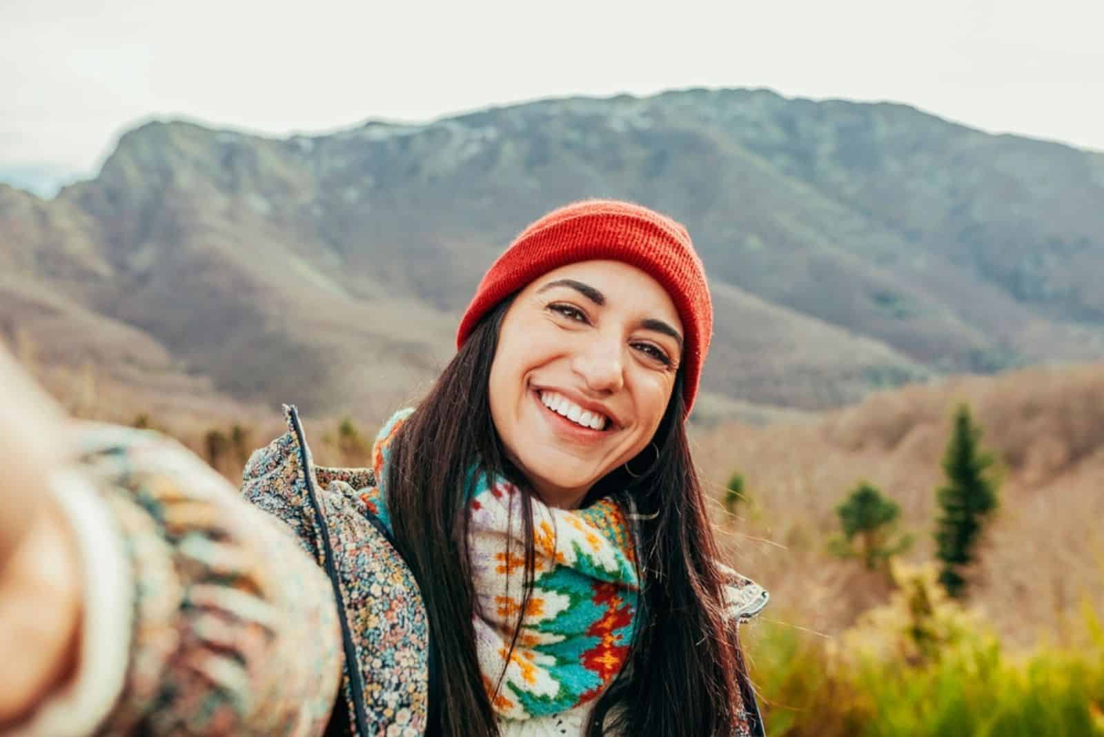 smiling woman takes a picture on the mountain