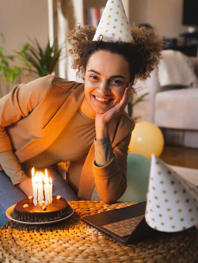 a woman in beige blazer with curly hair smiling in front of birthday cake