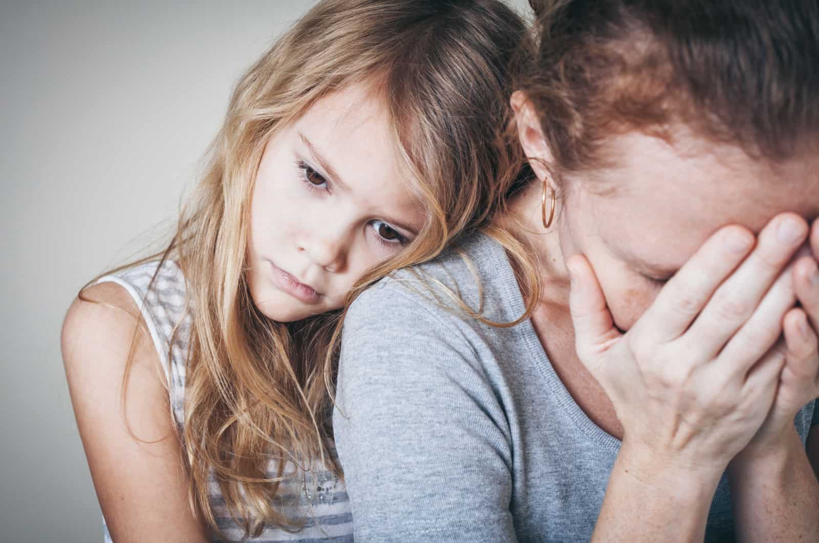 little girl comforting sad mother