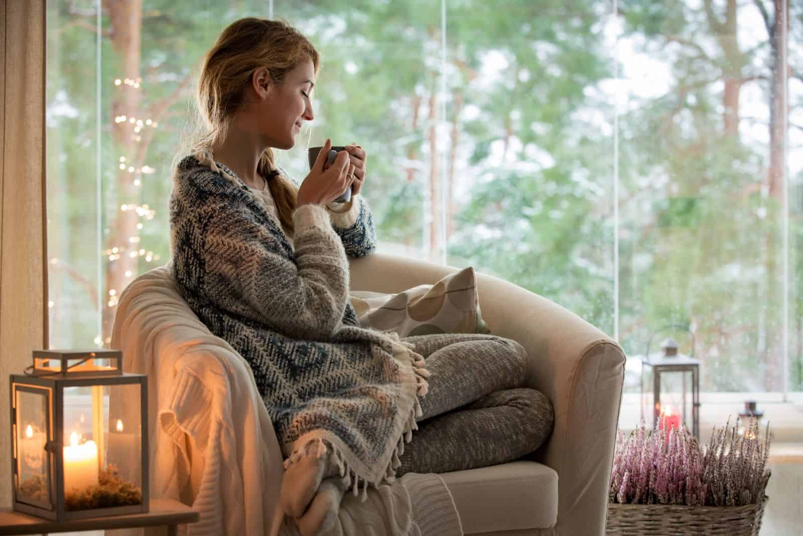 hermosa mujer sentada en un sillón disfrutando de un café