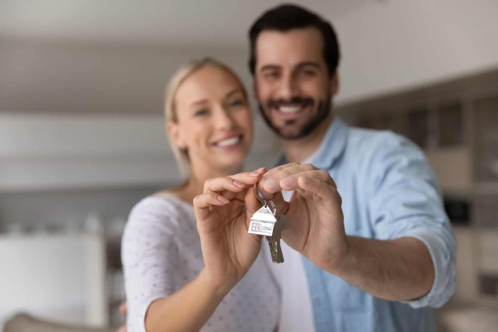 pareja muestra las llaves de su primer piso o casa en propiedad compartida