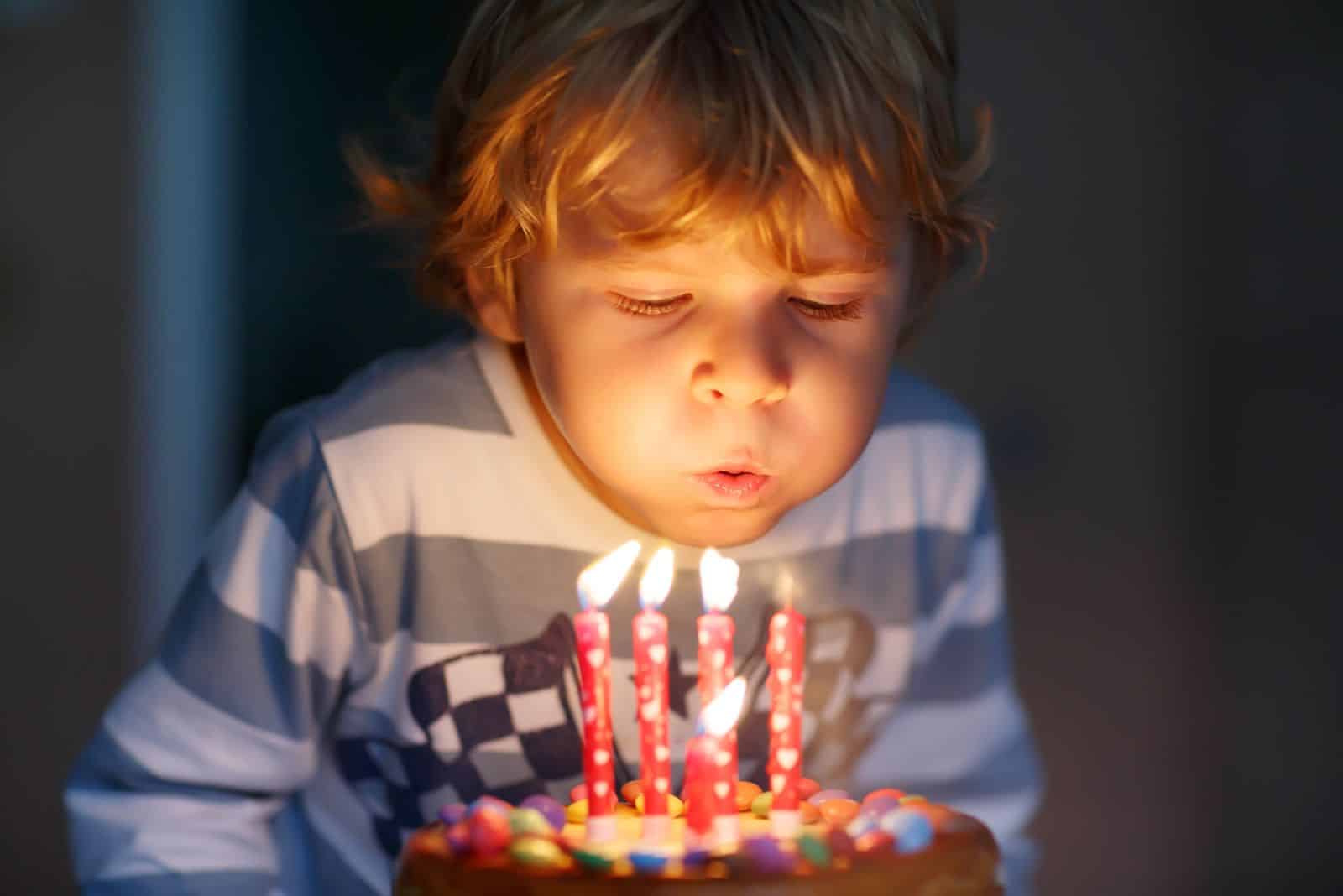 a child blows candles on a cake