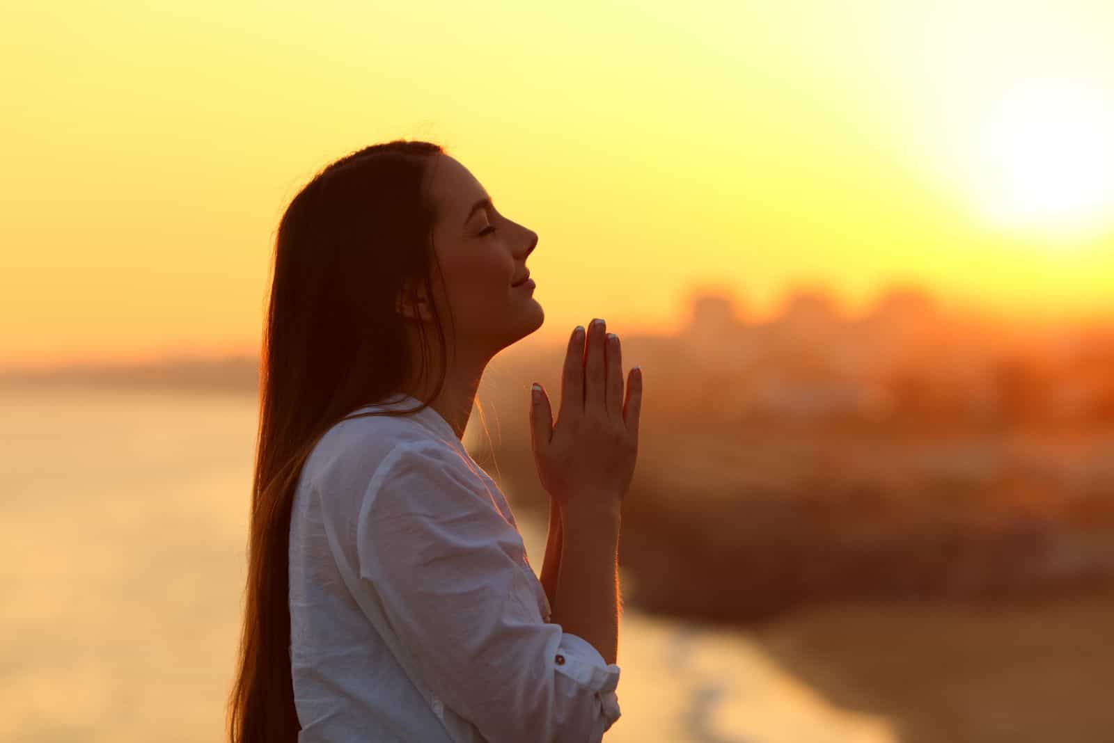 a beautiful woman stands in the open air and prays