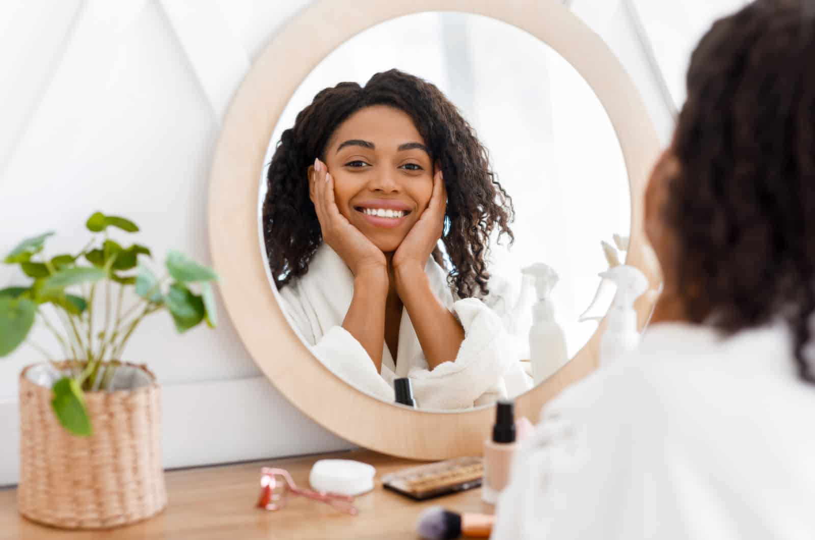 happy woman doing her skincare while looking in mirror