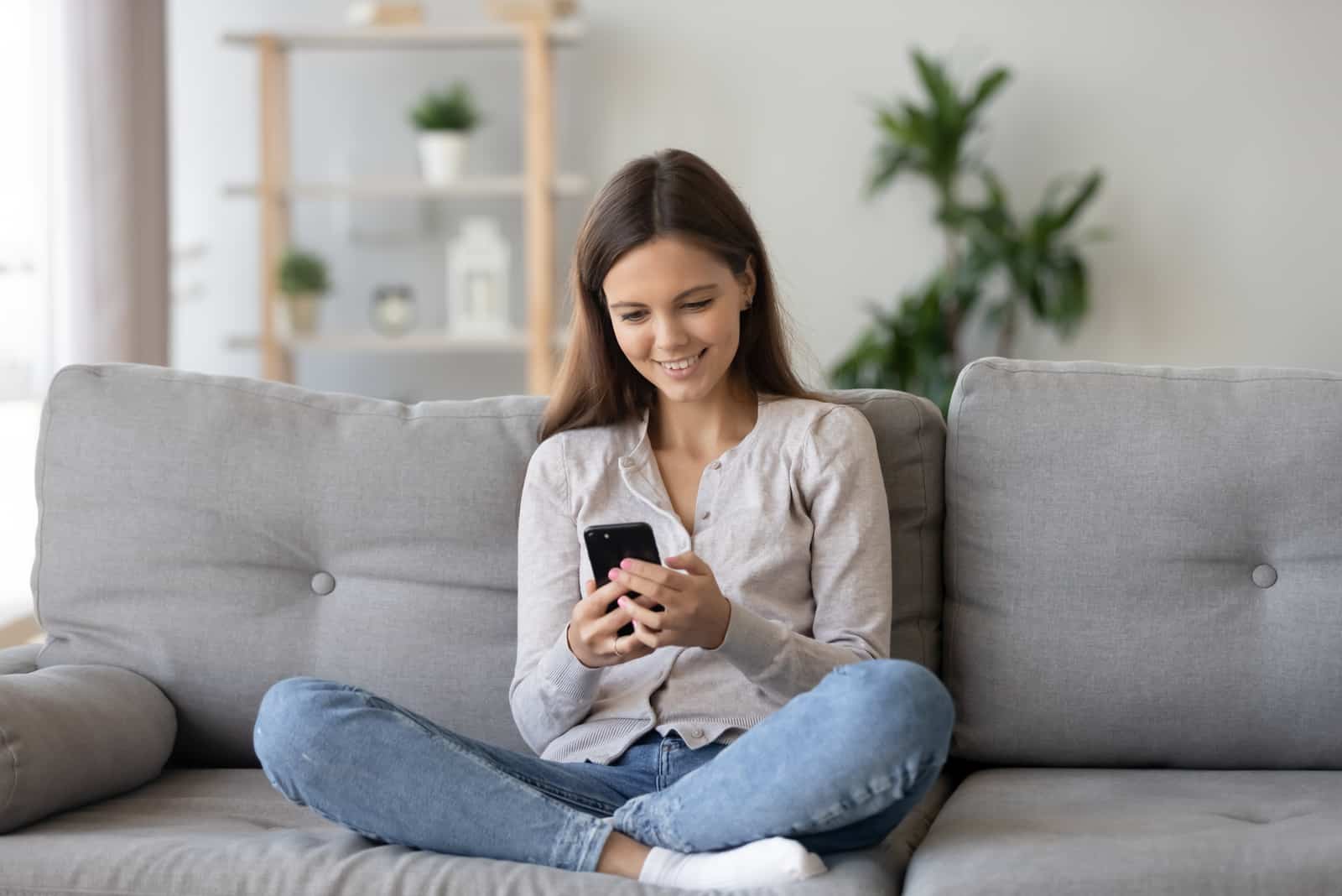 happy woman sitting on sofa while on her phone