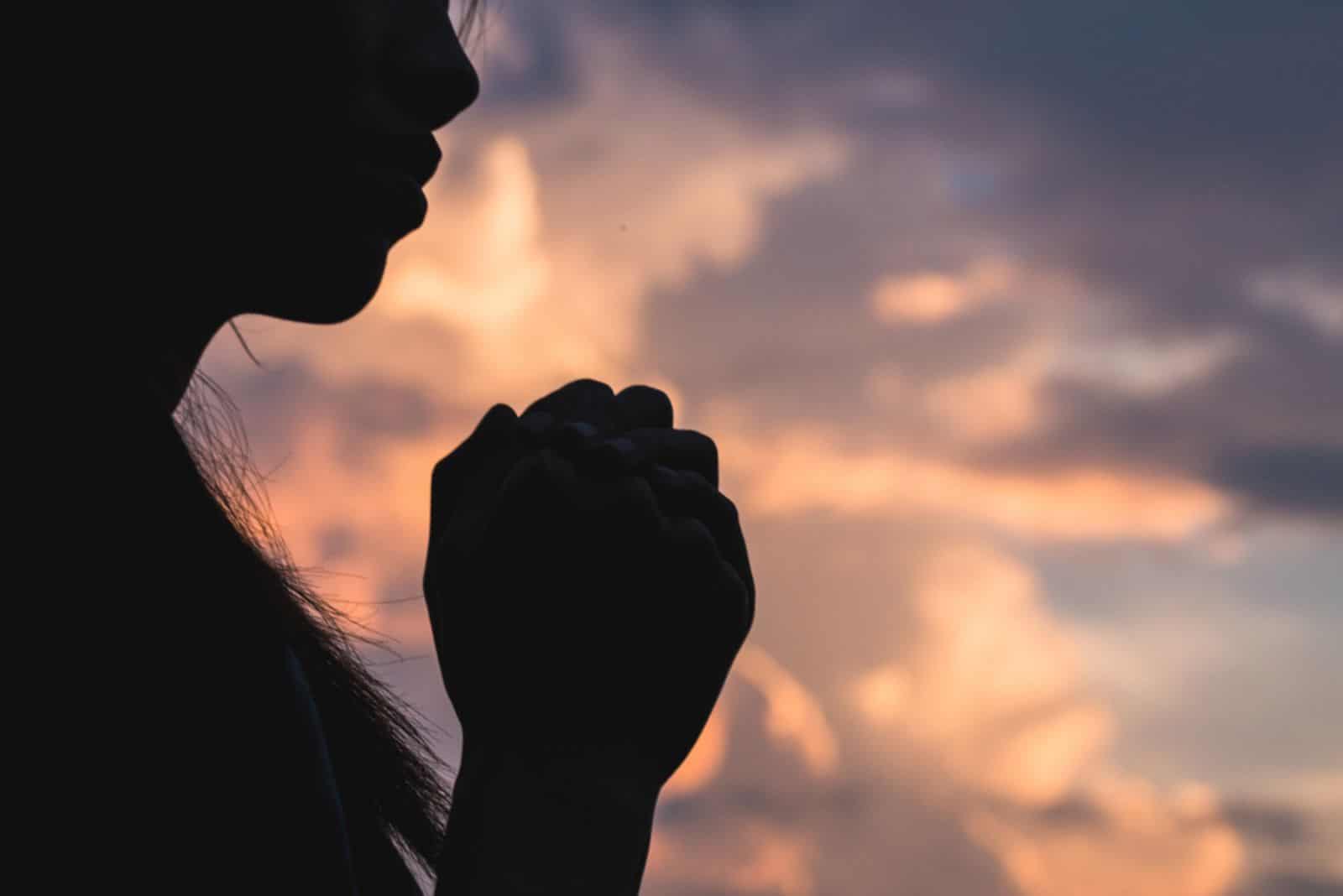 Silueta de mujer joven rezando por las bendiciones de Dios