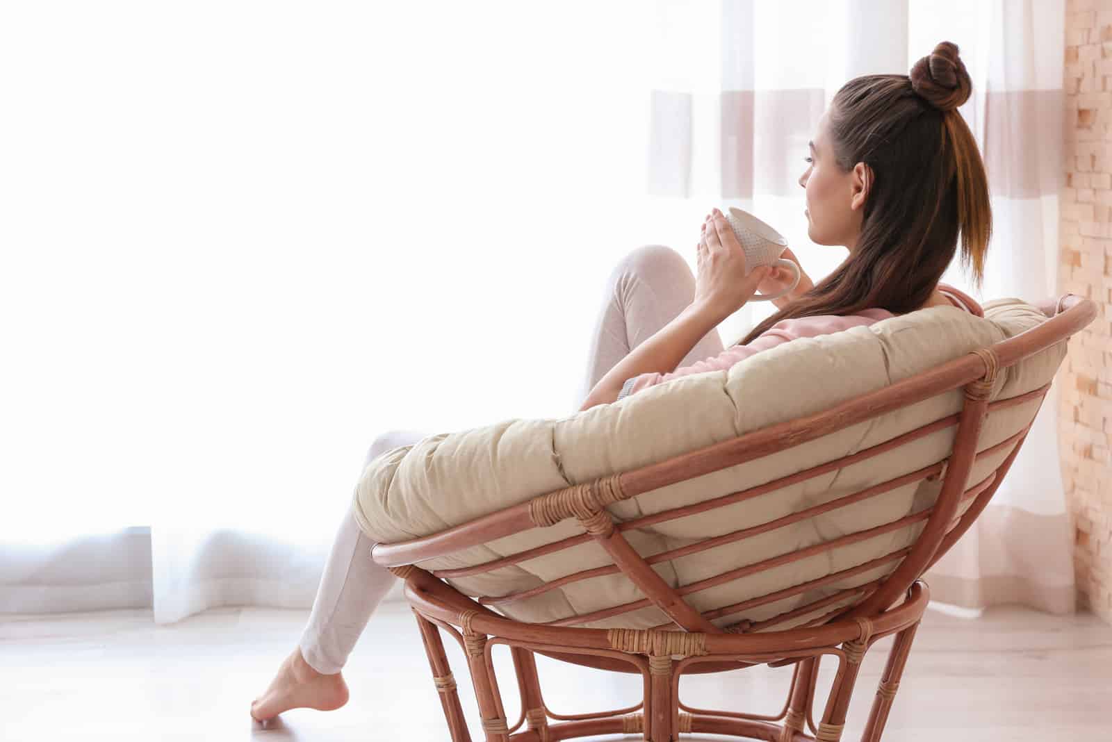 mujer sentada junto a una ventana bebiendo té