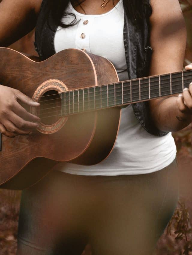 woman holding and playing a guitar
