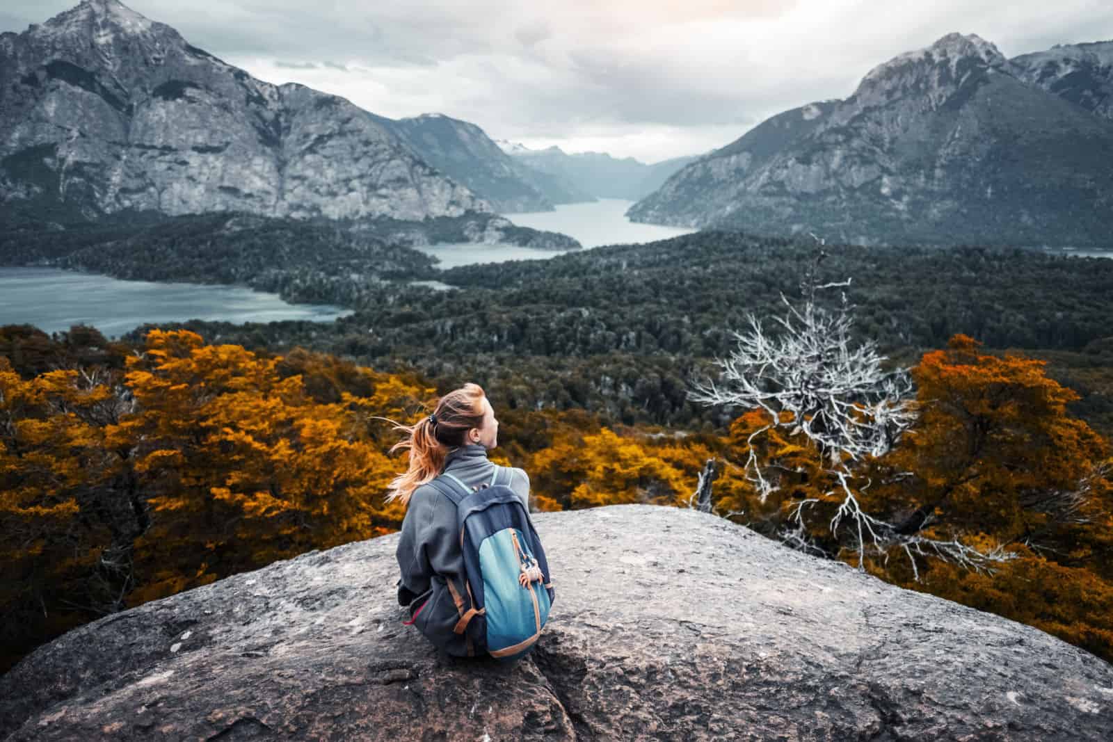 Woman hiker sits and enjoys valley view from viewpoint