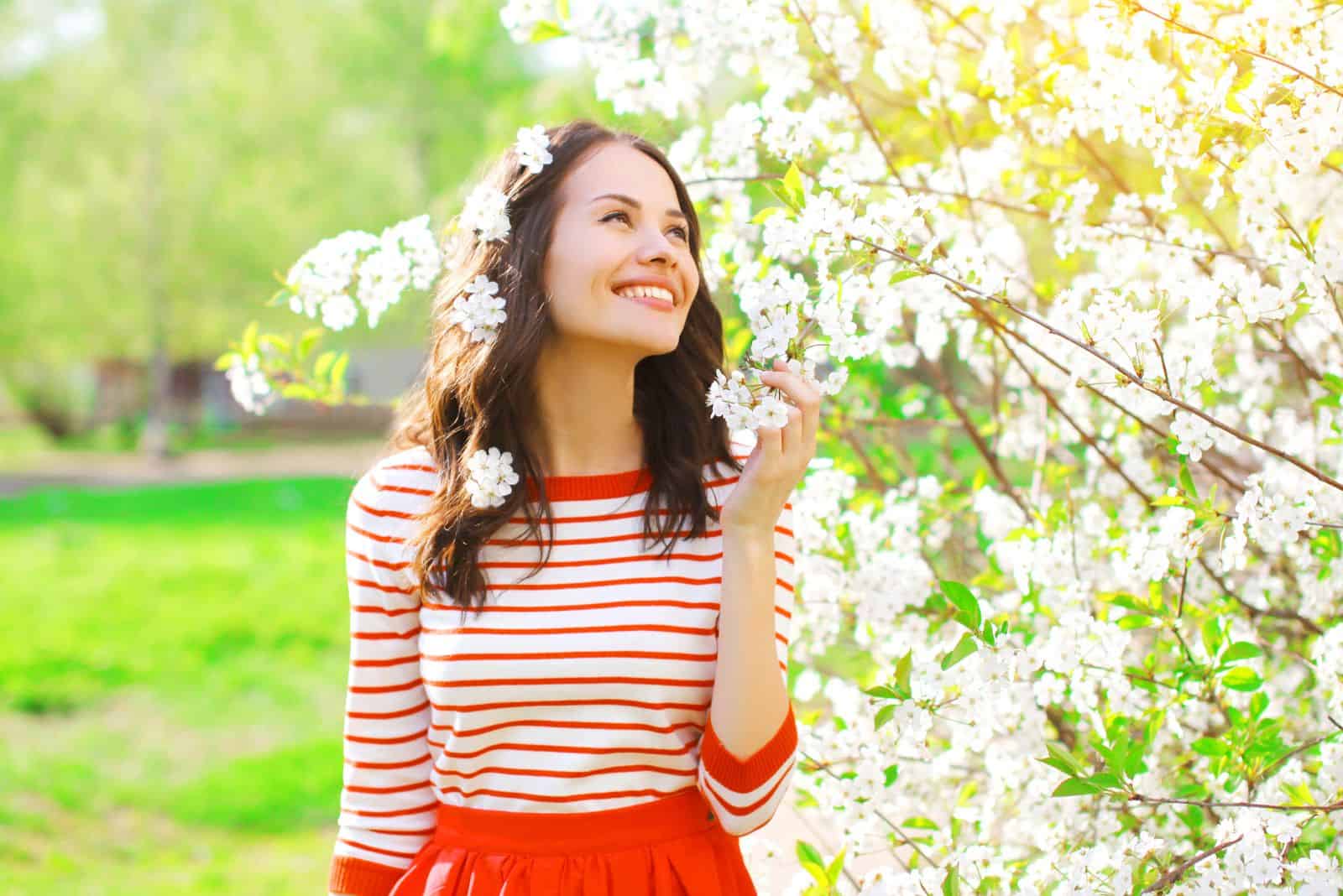 Happy smiling young woman with spring flowers at garden