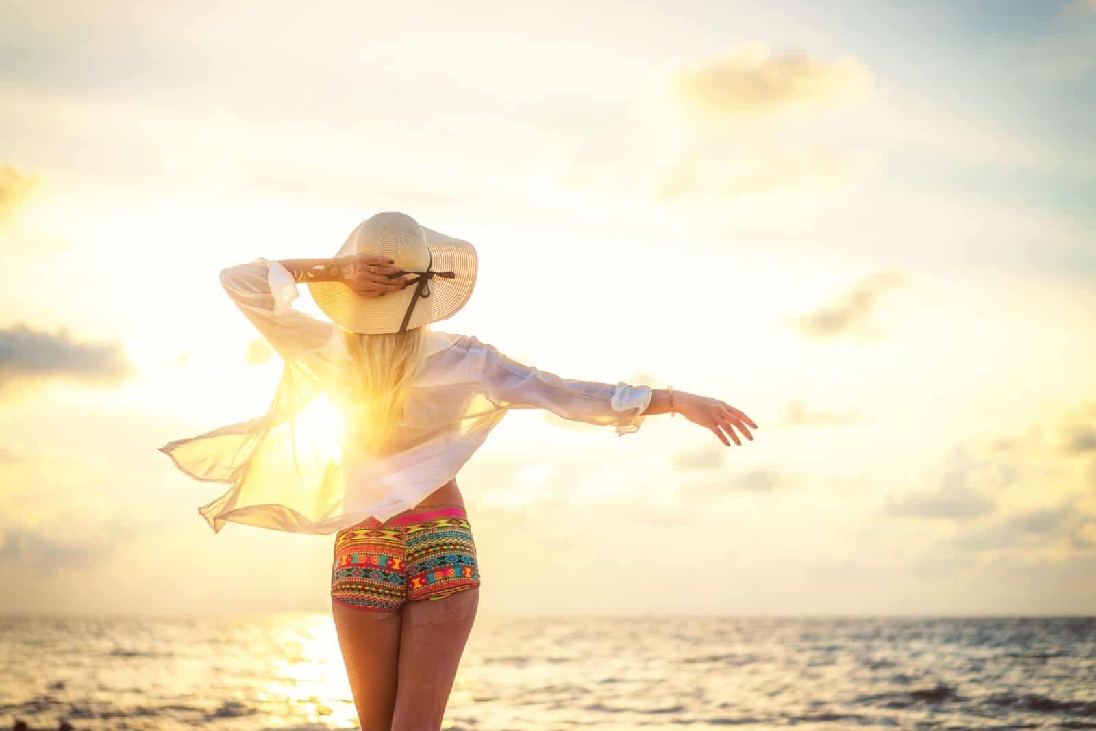 Woman in swiming suit posing on the beach at sunset