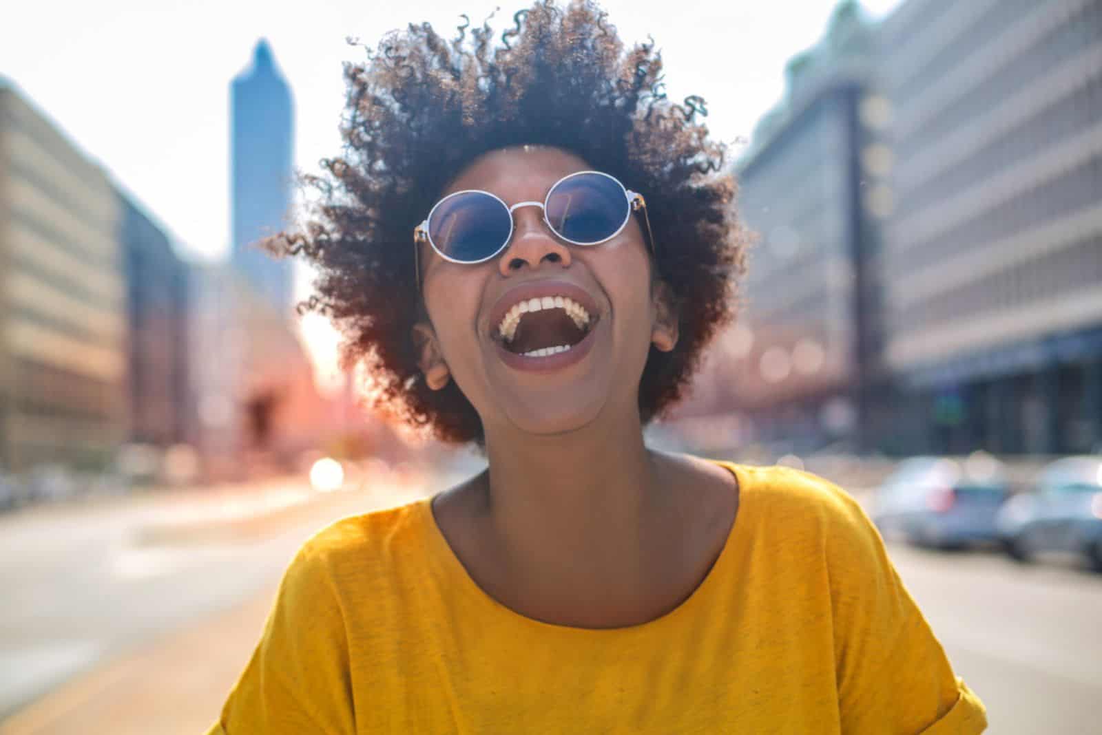 Chica alegre ríe en medio de una gran avenida