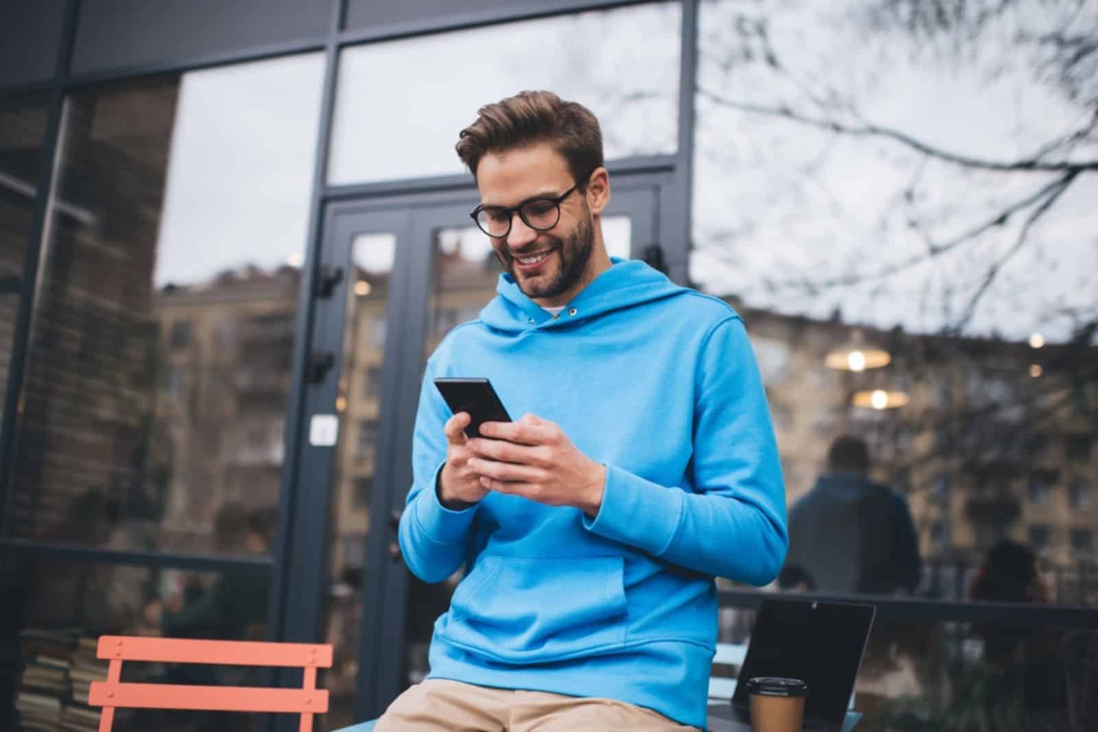 un hombre sonriente teclea en el teléfono