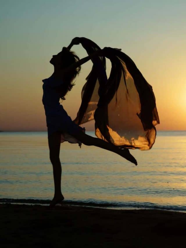 Silouette of the nifty woman dancing at the sea during sunset