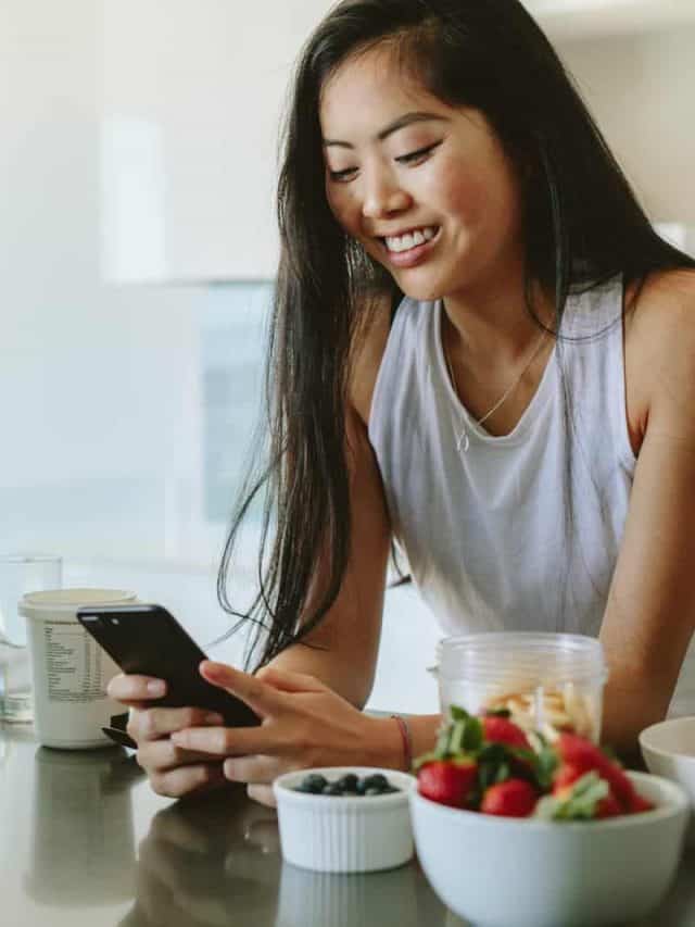woman standing in kitchen texting