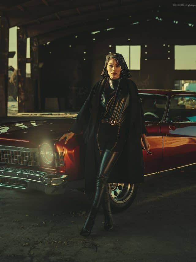 classy woman in black standing in front of a car