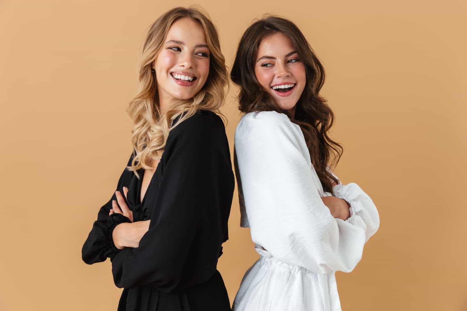 Retrato de dos mujeres felices con ropa blanca y negra sonriendo