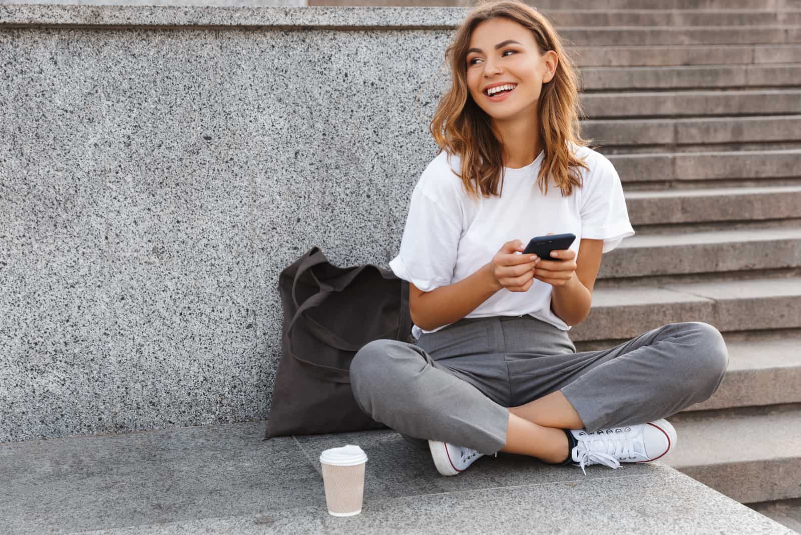 woman sitting outside typing on her phone