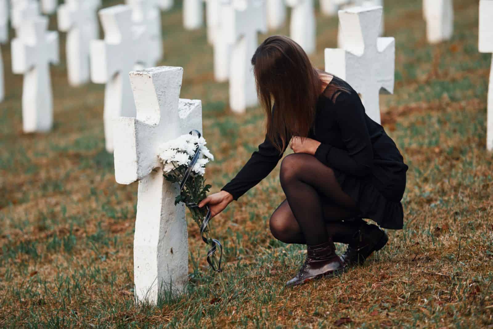 woman putting flowers on grave