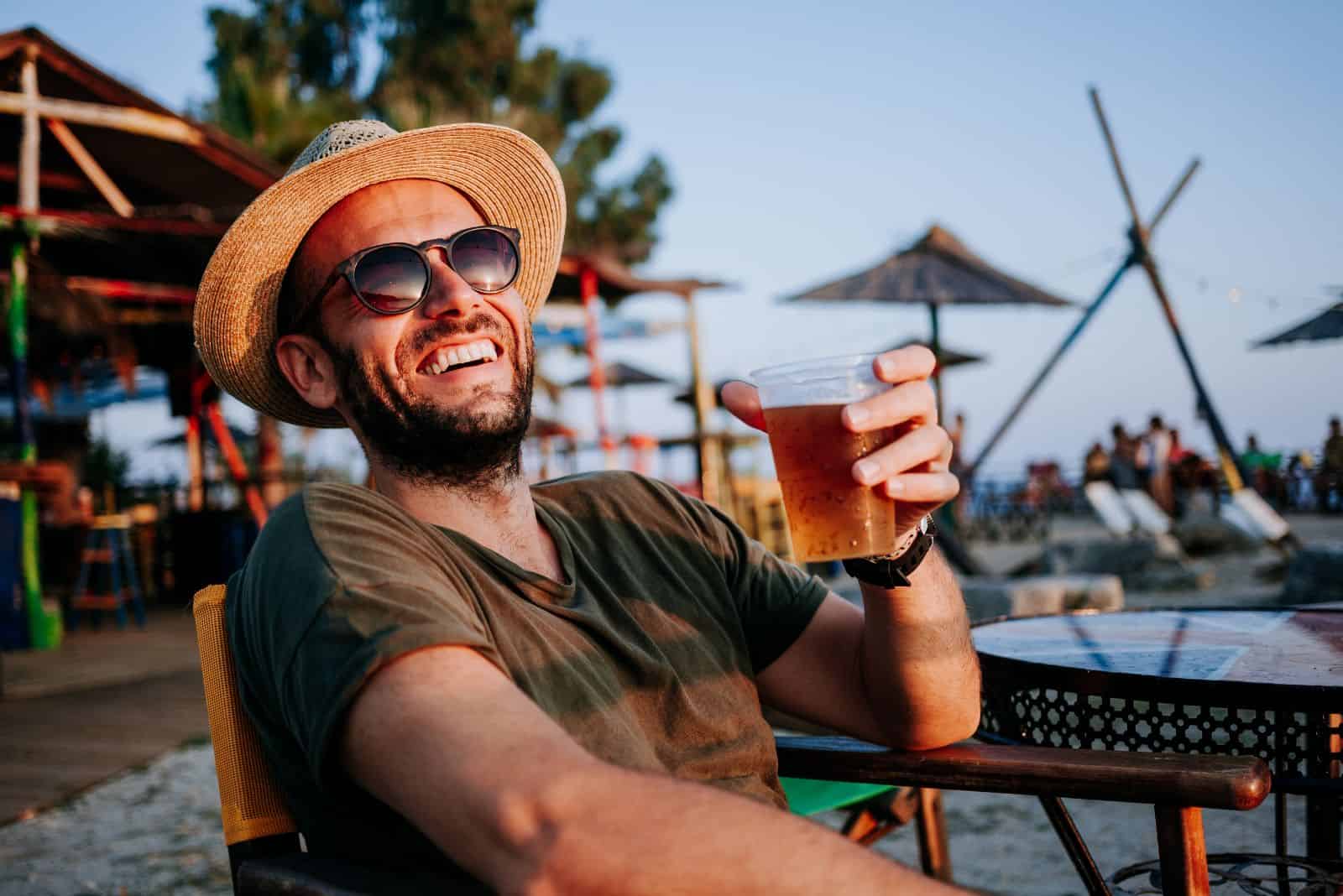 smiling man sitting and drinking beer