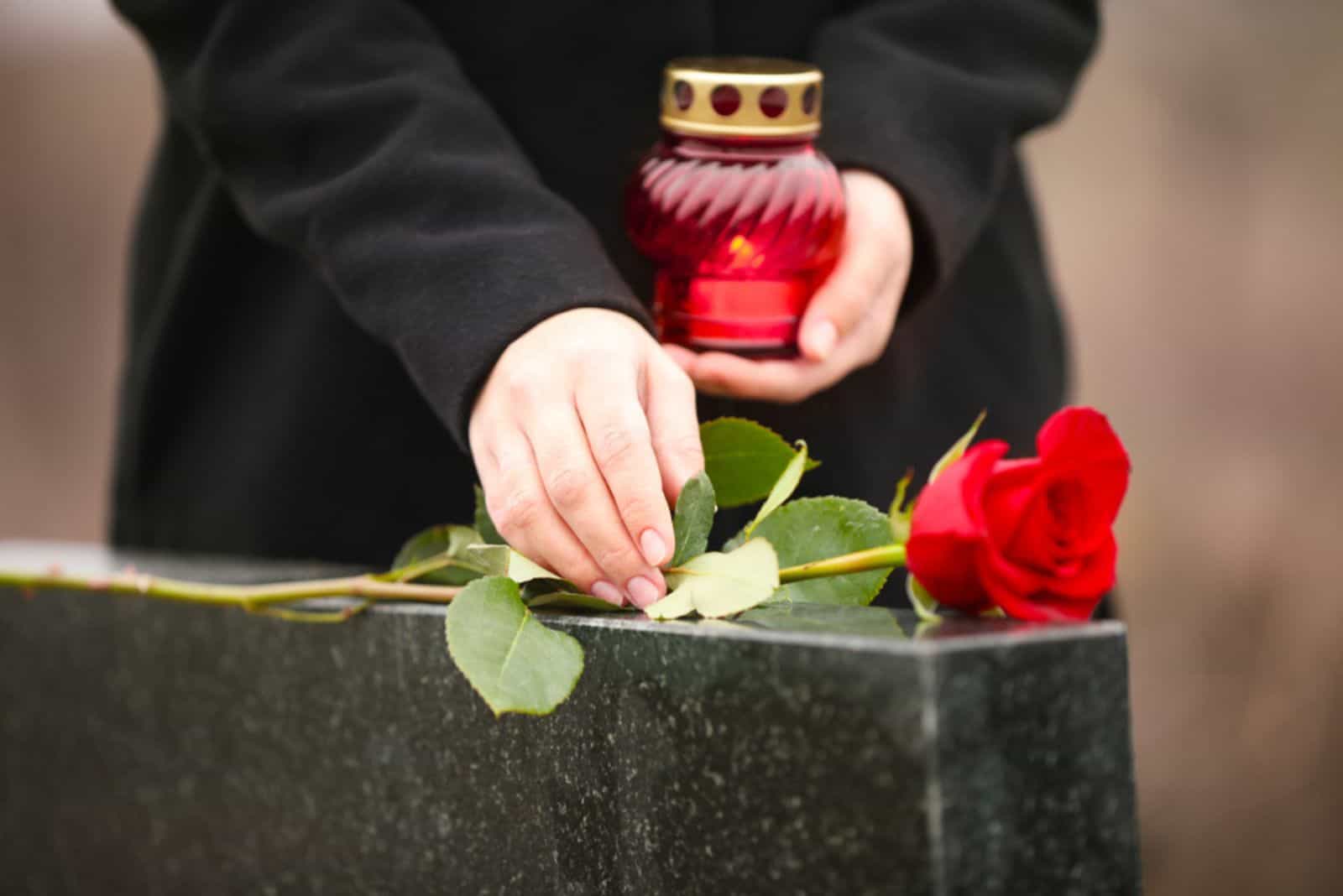 woman on grave with roses and a candle