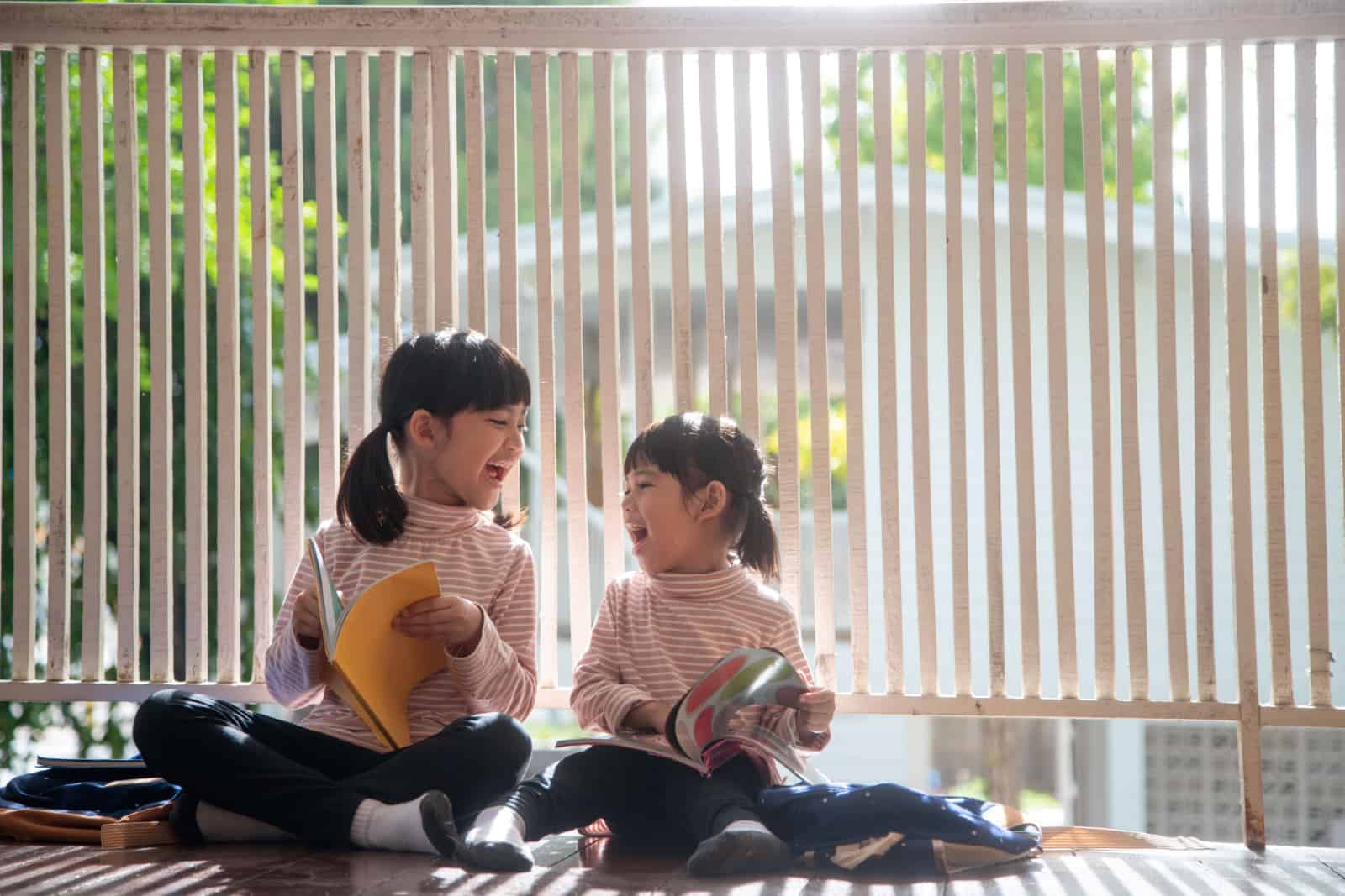 Cute Asian siblings girl reading a book at home