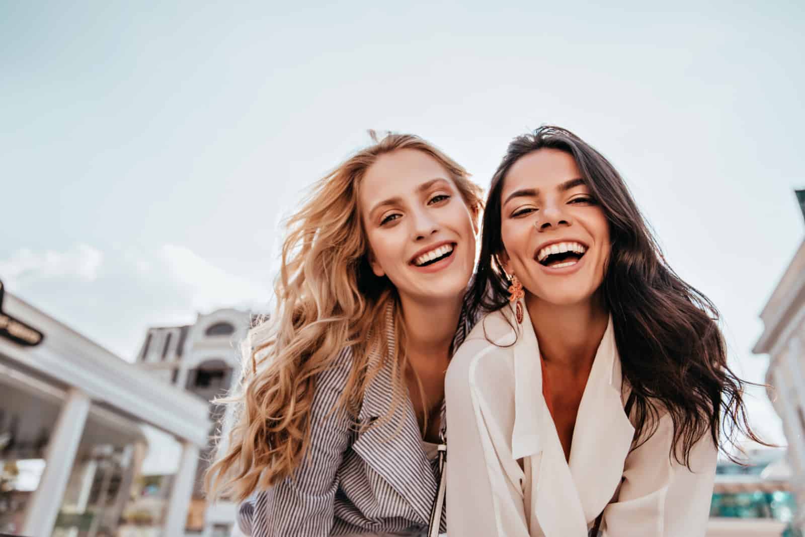 Inspired laughing ladies posing together on sky background.