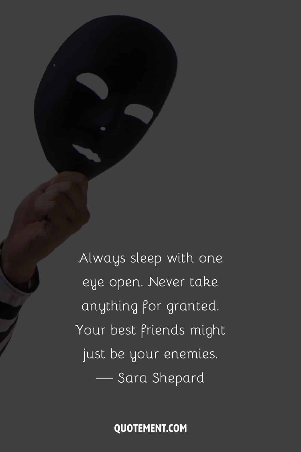 a hand holding a black mask image representing wise quote for fake friends