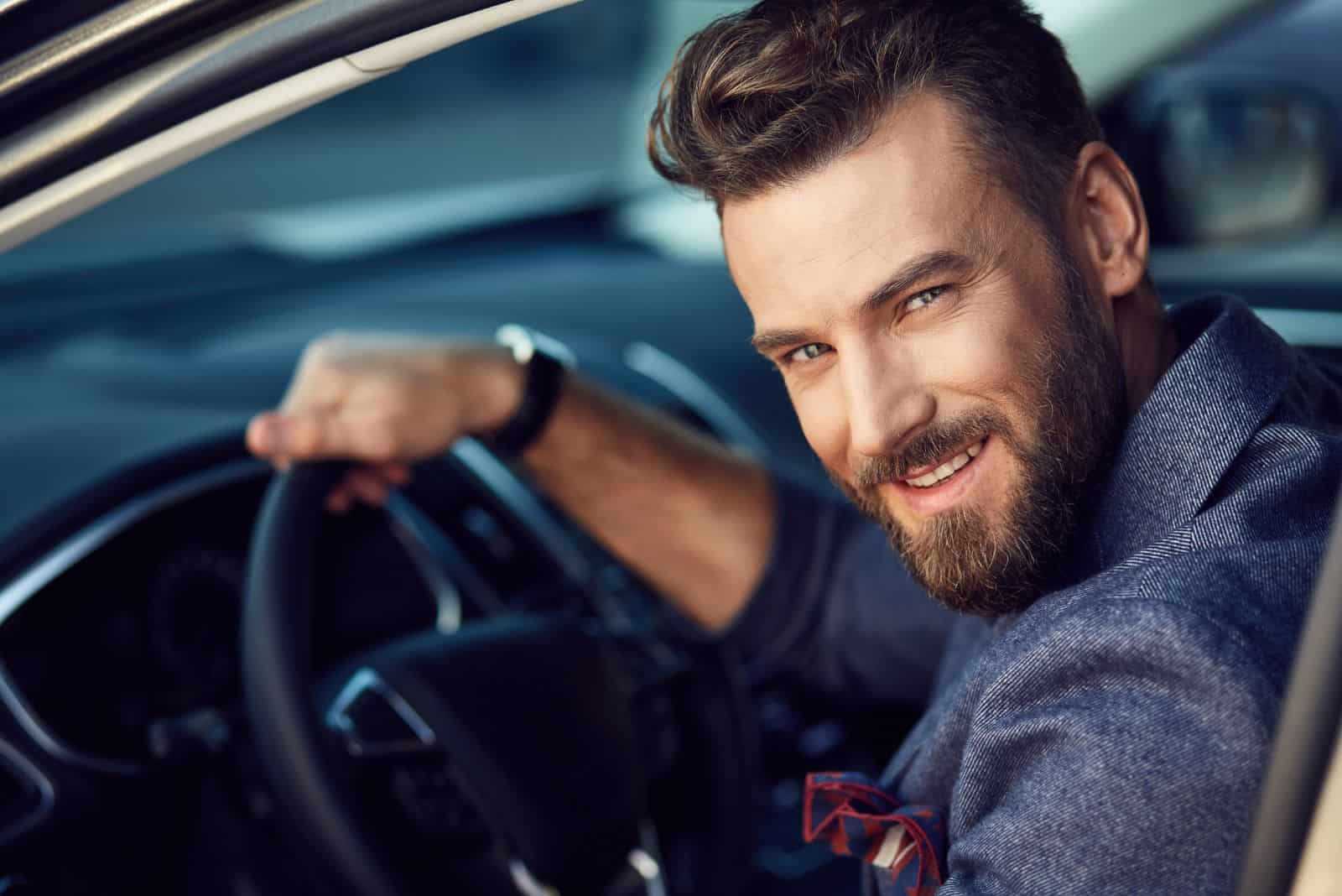 a smiling man is sitting in a car