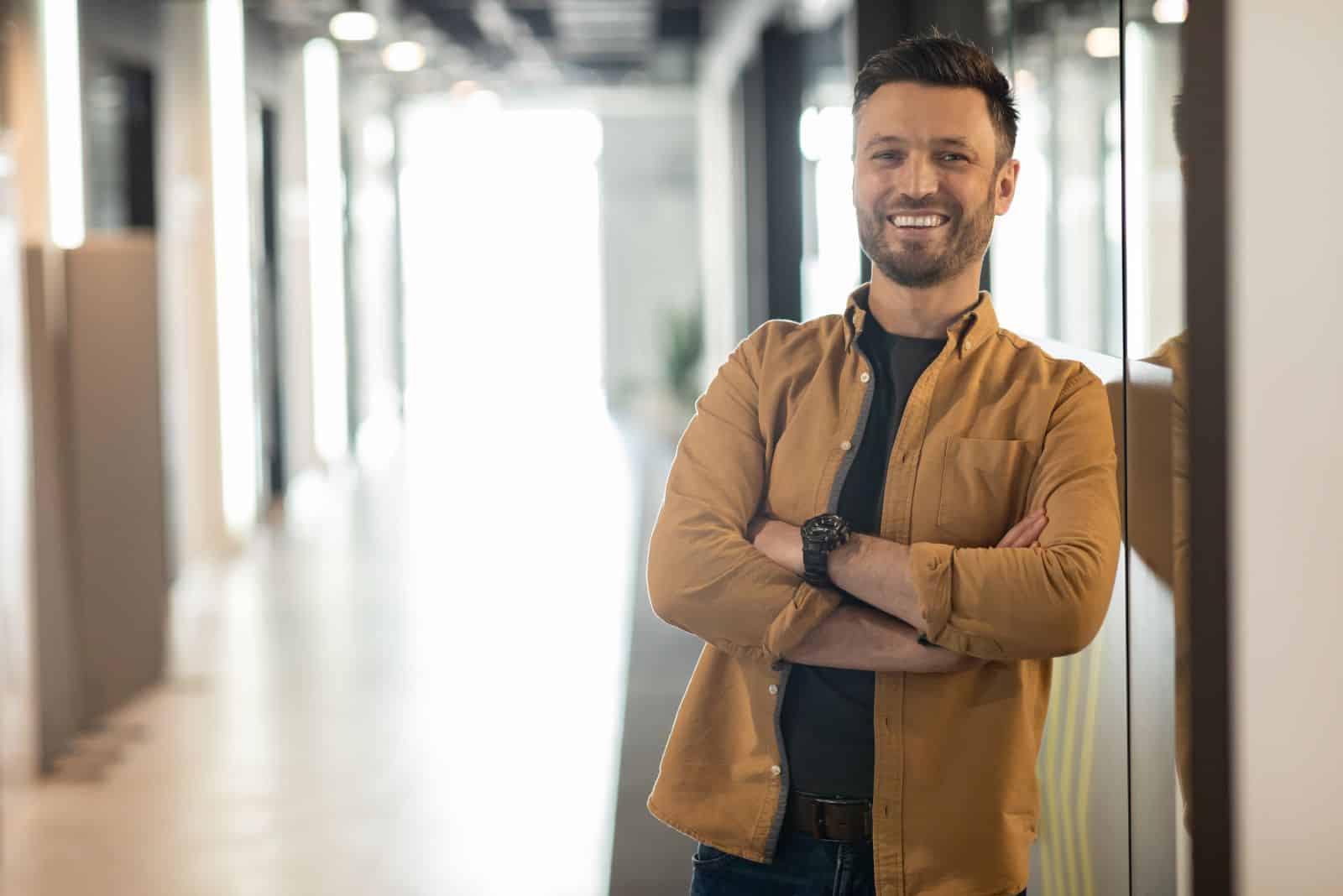 a smiling man leaning against a glass door