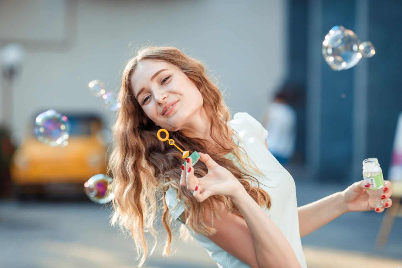 hermosa mujer feliz soplando pompas de jabón al aire libre