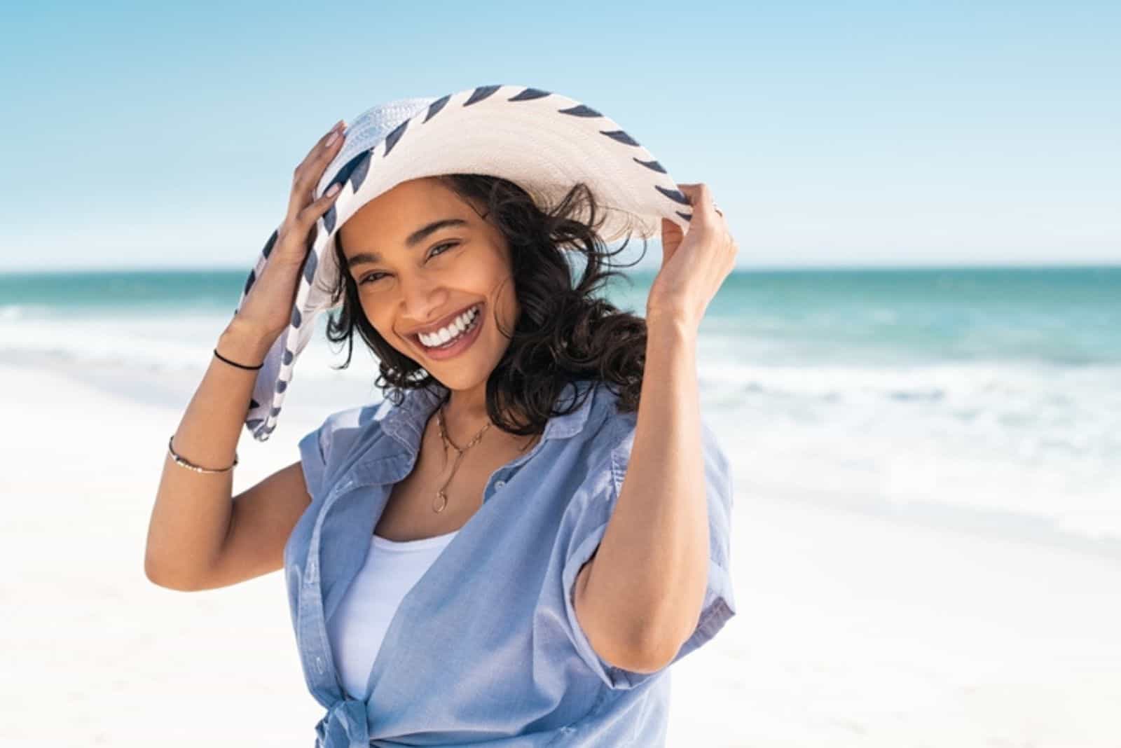 mujer con sombrero de paja blanco de pie en la playa