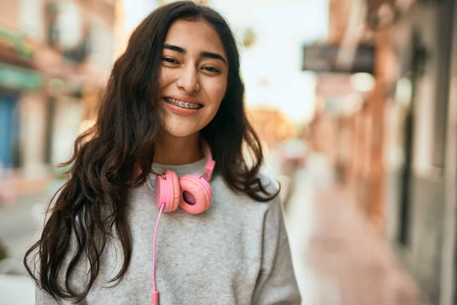 Joven chica de oriente medio sonriendo feliz usando auriculares en la ciudad.