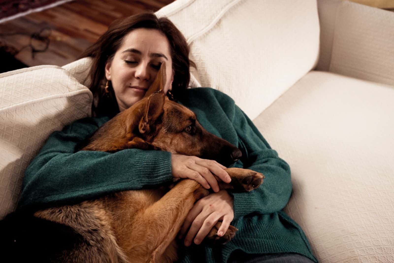 smiling woman cuddling with her dog on couch