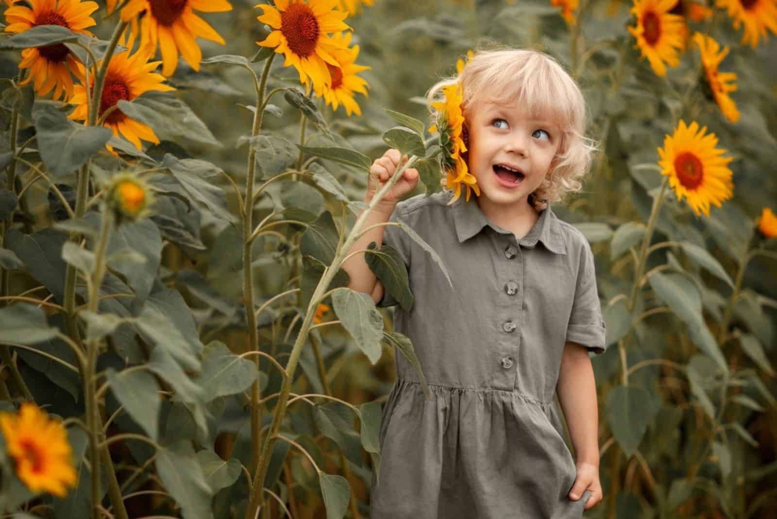 Cute little girl holds sunflower in hand and smiles