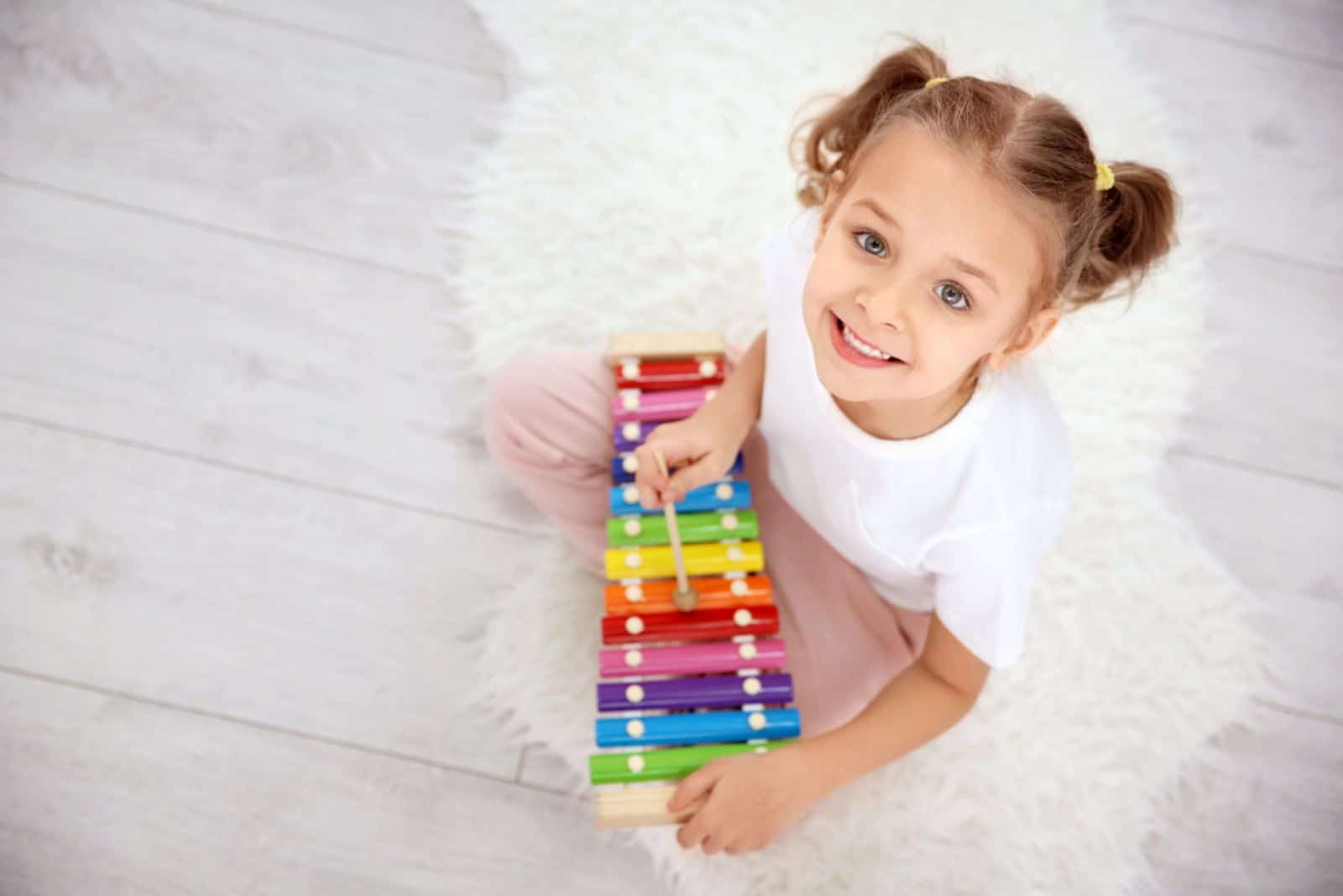 Cute little girl playing with xylophone at home
