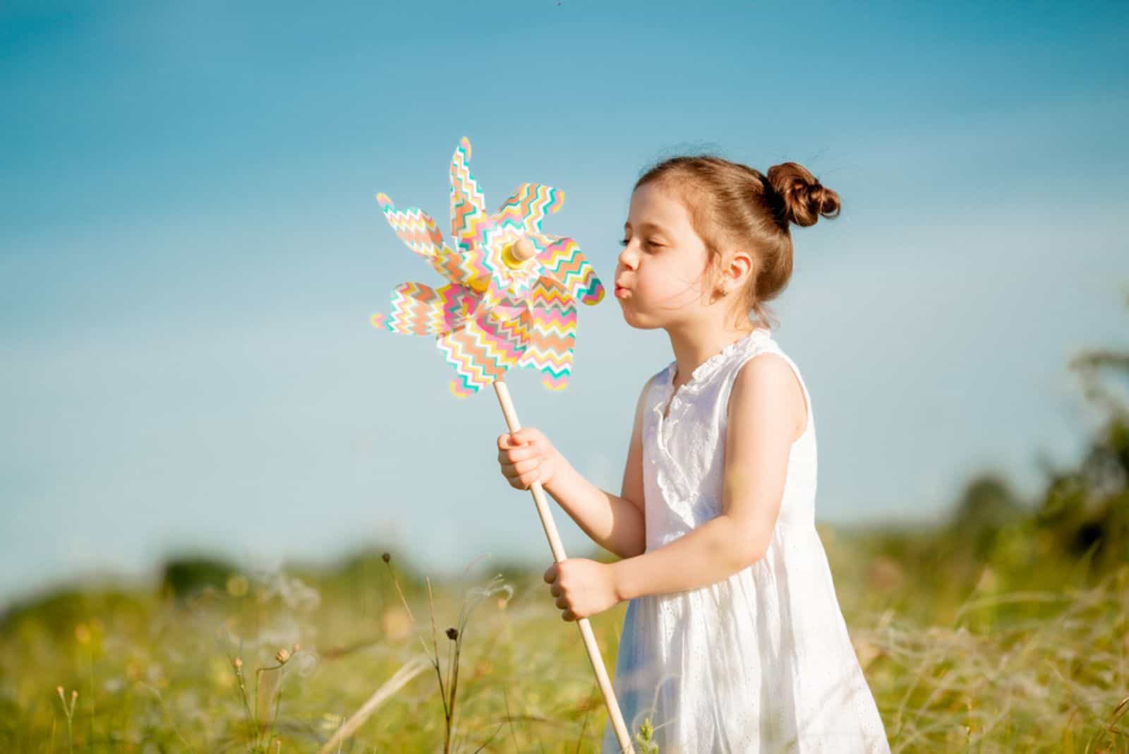 Cute little girl smiling summer in the field holding a windmill
