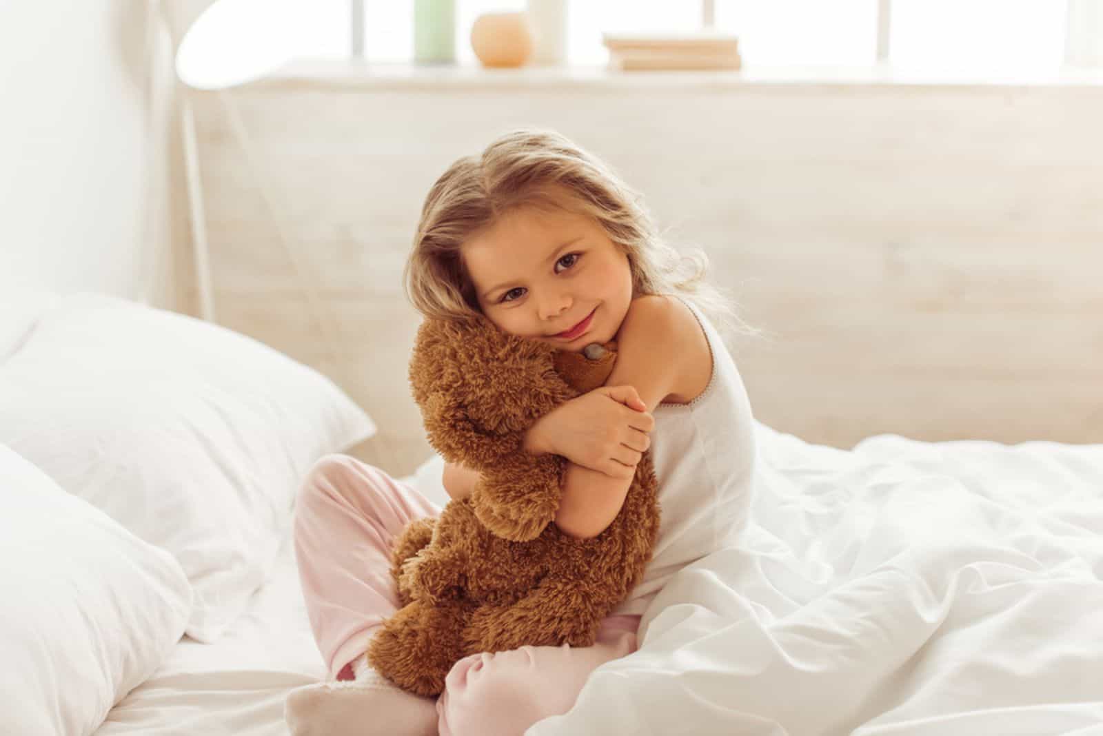 Sweet little girl is hugging a teddy bear