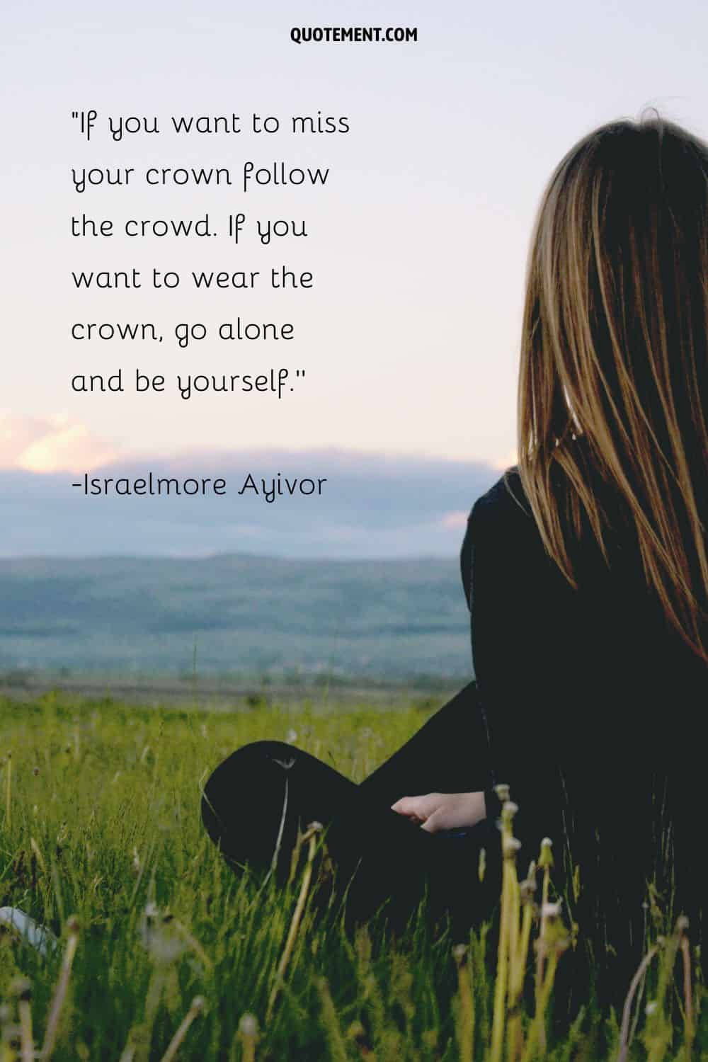 a girl in black sitting on the grass representing being alone inspirational quote
