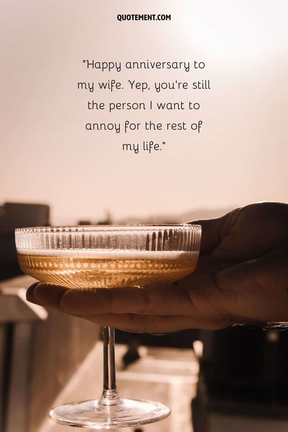 a hand holding a glass of drink representing funny anniversary quote