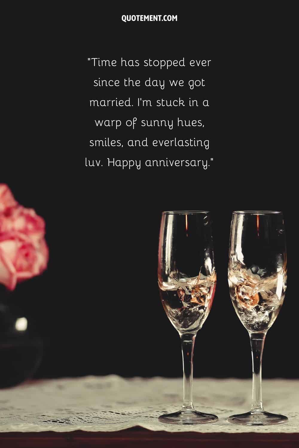 two glasses with champagne and wedding rings in them representing the loveliest happy anniversary quote for wife