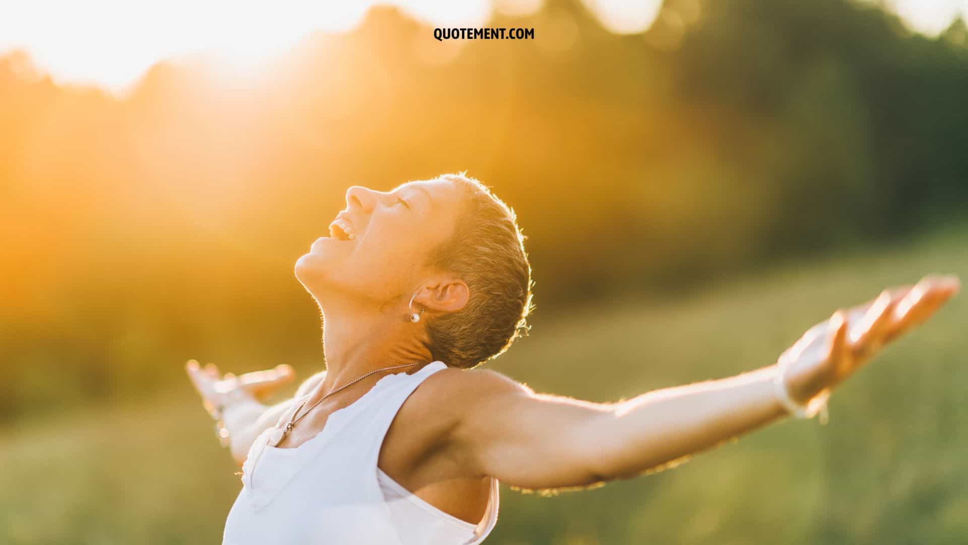 mujer sonriendo a la luz del sol con los brazos extendidos